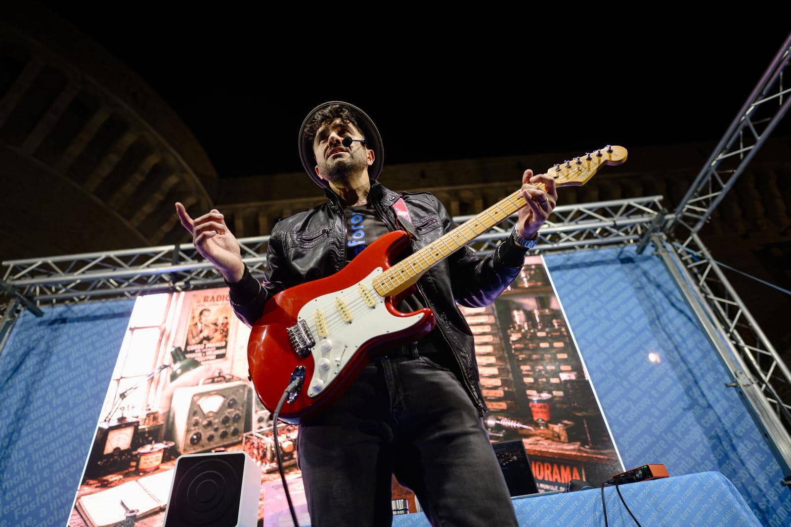 Un musicista suona la chitarra elettrica sul palco, di sera