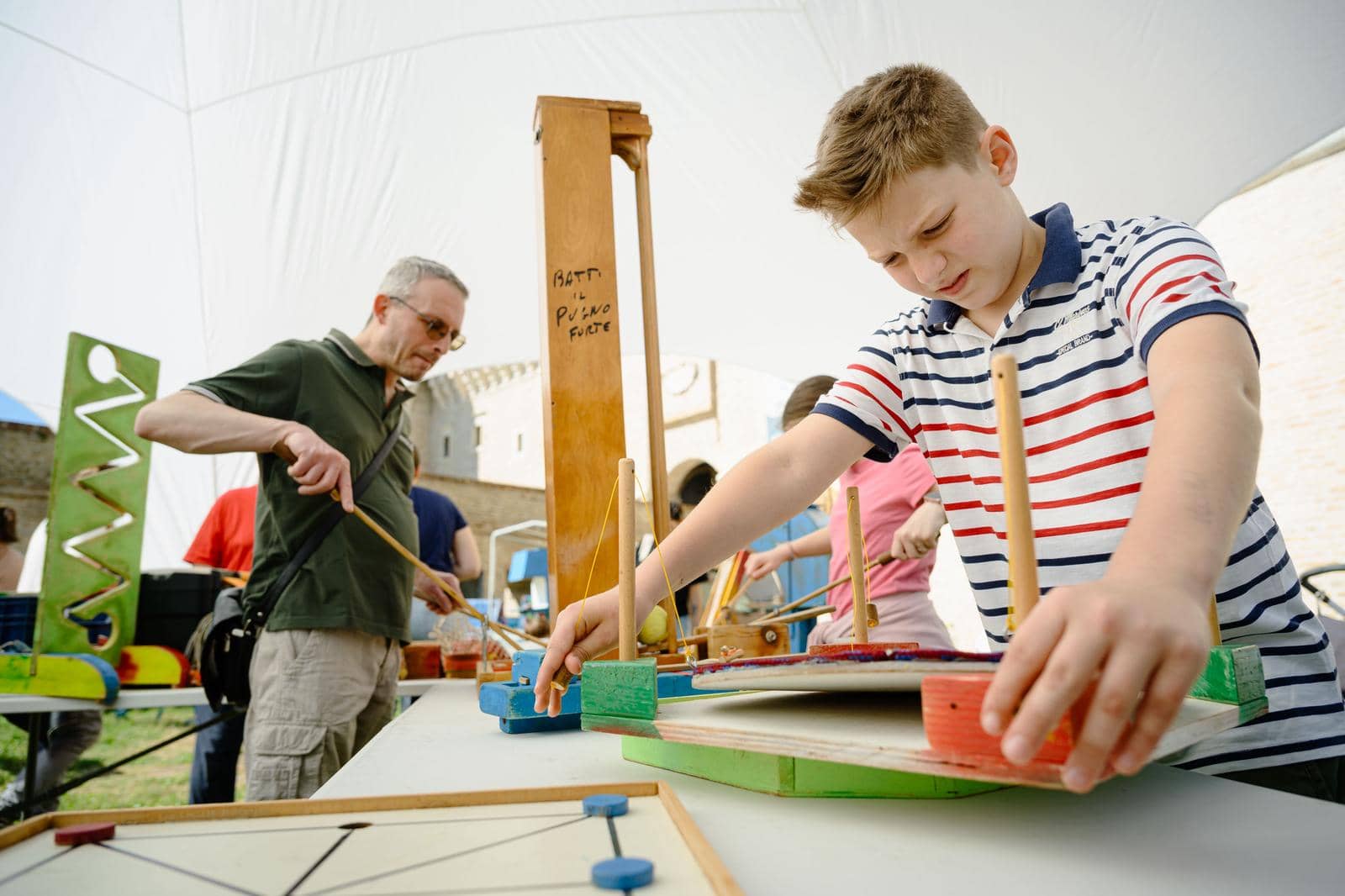 Un bambino monta un exhibit di legno durante un laboratorio sotto il gazebo